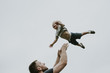 © Cavan Images - Playful father throwing son in air against clear sky