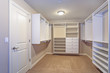 Large walk-in closet with white shelves, drawers