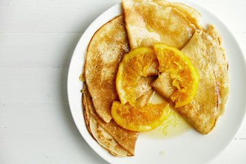 Wall Mural - Overhead image of pancakes with orange confiture in white plate on wooden table