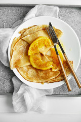 Wall Mural - Overhead image of pancakes with orange confiture in white plate on metallic tray on wooden table