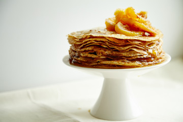 Wall Mural - Crepes cake with orange jam and honey on white cake stand. Pancake breakfast concept