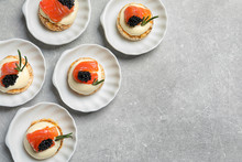 Tasty Appetizer With Black Caviar And Salmon On Plates