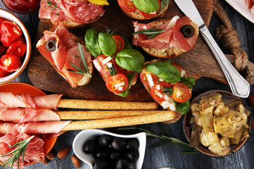 Italian antipasti wine snacks set. Cheese variety, Mediterranean olives, pickles, Prosciutto di Parma, tomatoes, artichokes and wine in glasses