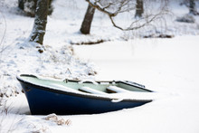 Dark Blue Rowboat Frozen In A Forest Lake.