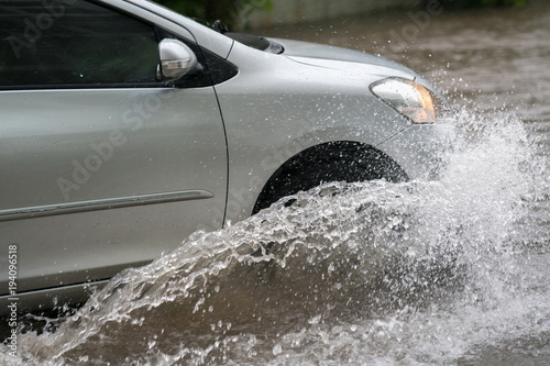 Zdjęcie XXL Samochód rozbija się przez wielką kałużę zalaną ulicą