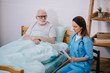 © LIGHTFIELD STUDIOS - Old man patient looking at nurse reading newspaper
