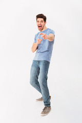 Wall Mural - Full-length photo of caucasian man in casual t-shirt and jeans smiling and pointing finger on camera meaning hey you, isolated over white background