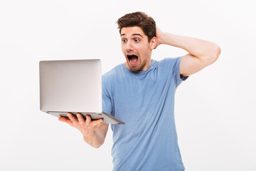 Sticker - Excited masculine man in casual t-shirt expressing delight while looking on screen of silver laptop in hand, isolated over white background