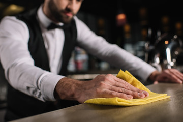 Wall Mural - cropped image of bartender cleaning bar counter in evening