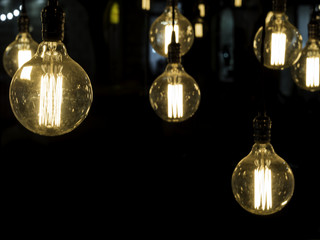 Filament antique looking light bulbs hanging from ceiling against black background