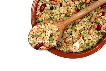 Mixed dried legumes and cereals in clay bowl with wooden spoon isolated on white background