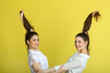 © Alexandr - two beautiful joyful sisters twin girls in white blouses on a yellow background