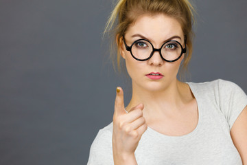 Woman wearing eyeglasses pointing at camera