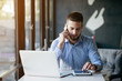 © Cressida studio - Young handsome man sitting in office with cup of coffee and working on project connected with modern cyber technologies. Businessman with notebook trying to keep deadline in digital marketing sphere.