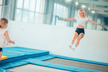 Twine young woman jumping on trampoline club