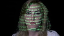 Green Binary Code Projected On The Face Of An Sexy Smart Software Developer Female With Blonde Hair In A Dark Room