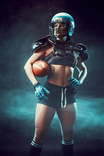 Sportive Serious Woman In Helmet Of Rugby Player Holding Ball In Stuio On Dark Background. Side View, Smoke