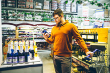 Man Choose Alcohol In Store. Shopping Concept. Bottle In Man Hands