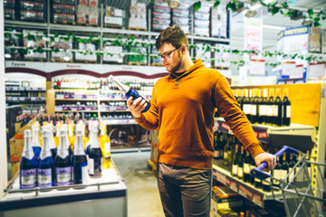 Wall Mural - man choose alcohol in store. shopping concept. bottle in man hands