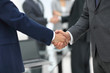 © ASDF - Business partners handshaking over business objects on workplace