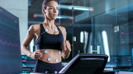 Wall Mural - beautiful woman athlete runs on a treadmill with electrodes attached to her body, female physician u