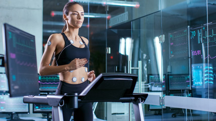 Wall Mural - beautiful woman athlete runs on a treadmill with electrodes attached to her body, female physician u