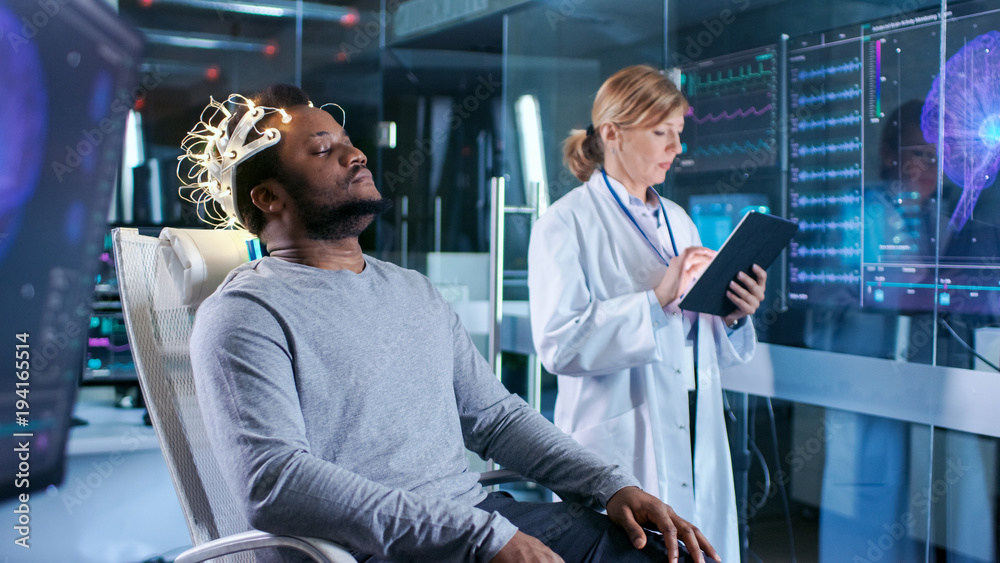 Man Wearing Brainwave Scanning Headset Sits in a Chair while Scientist ...