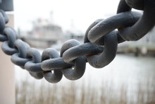 Huge Black Anchor Chain Hanging Between Two Posts In A Shipyard