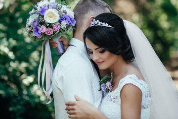 Wall Mural - Bride leans to groom tender hugging in the forest