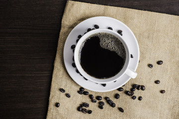 Black coffee in white cup and coffee bean on wood table background.