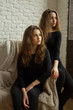 © Alexandr - two beautiful young girl sisters twins with flowing hair in black clothes against a white brick wall background
