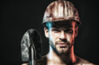 Man with confident face expression isolated on black background. Construction, work and mining concept. Builder or miner wears protective helmet holds shovel. Copy space in upper corner.