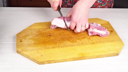 Wall Mural - Woman chef throws sliced meat on a cutting board in the home kitchen. Hands Cutting Fresh Meat, Cutting Meat on a Kitchen Board, Cutting Raw Meat. Cooking food at home.