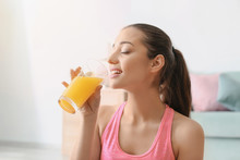 Beautiful Sporty Woman Drinking Juice After Doing Fitness Exercises At Home