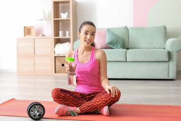 Wall Mural - Beautiful young woman with bottle of water after doing fitness exercises at home