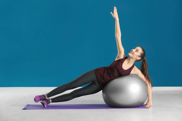 Poster - Beautiful young woman doing fitness exercise with ball at home