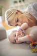 © Mladen - Mother enjoying with her little baby boy at home and playing with her. Close up.