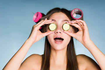 Wall Mural - woman on a blue background holds in her hands cucumber slices