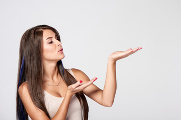 Closeup side view of beautiful brunette woman blowing on palms to the side at blank copy space