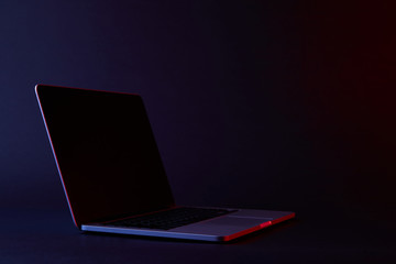 one turned off laptop with reflecting screen on dark