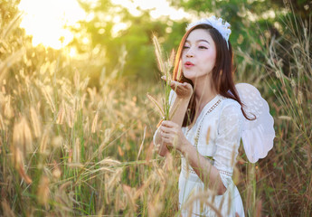 Wall Mural - angel woman in a grass field with sunlight