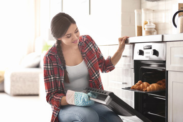 Poster - Woman baking croissants in oven indoors