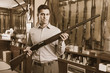 © JackF - Glad male hunter choosing shotgun in store