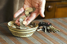 Man Placing Loose Change In Bowl At Home With Car Keys