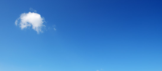 Panoramic photo with small cloud on bright blue sky background.