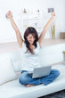 © auremar - woman with laptop on crossed legs making gesture of triumph