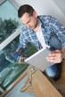 © auremar - carpenter cutting wood while checking tablet