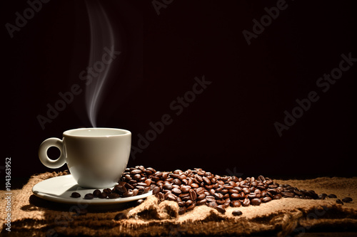 Plakat Filiżanka kawy z dymnymi i kawowymi fasolami na czarnym tle