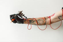 Hand Tattoo Artist With The Tattoo Machine On A White Background. The Red Wires