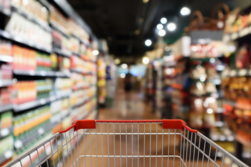 Wall Mural - Shopping cart with supermarket aisle blur abstract background